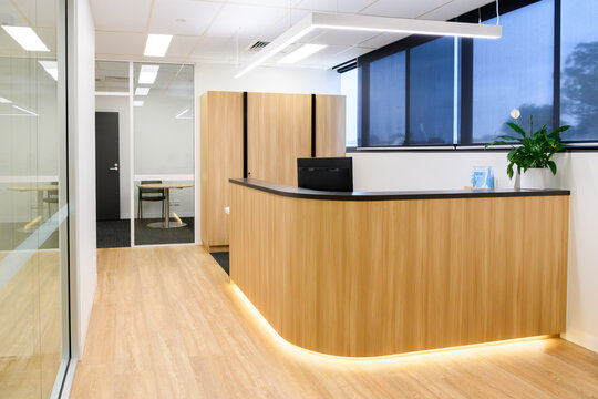 A generic reception area in a modern office, with wooden floors and a wooden faced counter - horizontal
