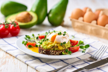 Avocado toast with poached egg over rye bread toast with mashed avocado spread. Healthy breakfast or lunch food.