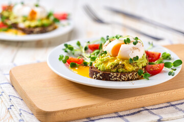 Breakfast with poached egg toast with avocado and tomatoes vegetarian food.