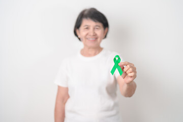 Elderly with Green Ribbon for concept of March world Bipolar disorder day, Cerebral Palsy Awareness month, kidney disease Cancer and Traumatic Brain Injury, TBI. Healthcare and world cancer day