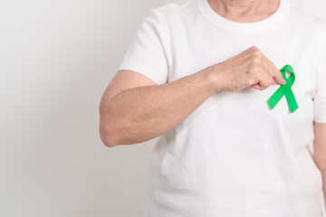 Elderly with Green Ribbon for concept of March world Bipolar disorder day, Cerebral Palsy Awareness month, kidney disease Cancer and Traumatic Brain Injury, TBI. Healthcare and world cancer day