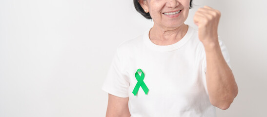 Elderly with Green Ribbon for concept of March world Bipolar disorder day, Cerebral Palsy Awareness month, kidney disease Cancer and Traumatic Brain Injury, TBI. Healthcare and world cancer day