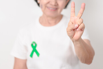 Elderly with Green Ribbon for concept of March world Bipolar disorder day, Cerebral Palsy Awareness month, kidney disease Cancer and Traumatic Brain Injury, TBI. Healthcare and world cancer day