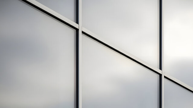 A modern architectural detail showcasing a bright, geometric frosted glass facade with clean lines and reflective panels, viewed close-up on a sunny day - Powered by Adobe