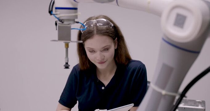 Female engineering student adjusts suction gripper with white glove during robot arm training for precision movement in collaborative automation system inside smart robotics education lab
