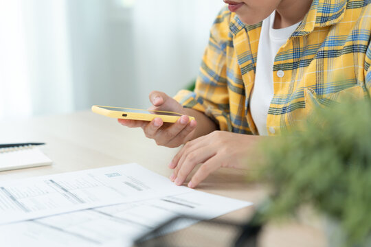 woman use phone scan barcode or QR codes to pay credit card bill after receiving document invoice. payment, receive, paying electricity, digital payments, technology, scanning, financial transactions - Powered by Adobe