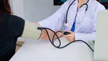 Close up asian female doctor sitting at desk using measure blood pressure checking patient in medical clinic hospital presenting results examination preventive care healthcare services consultation.