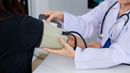 Close up asian female doctor sitting at desk using measure blood pressure checking patient in medical clinic hospital presenting results examination preventive care healthcare services consultation.