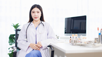 Portrait confident asian female doctor sitting working at desk in professional office medical clinic hospital with computer stethoscope documents system physician expertise in healthcare consultation