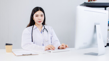 Portrait confident asian female doctor sitting working at desk in professional office medical clinic hospital using computer stethoscope documents system physician expertise in healthcare consultation