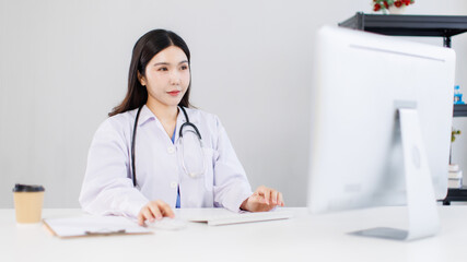 Portrait confident asian female doctor sitting working at desk in professional office medical clinic hospital using computer stethoscope documents system physician expertise in healthcare consultation