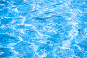 
Close-up of bright blue swimming pool water surface with sunlight reflections and ripples, refreshing summer vacation and tropical luxury background.concept relex