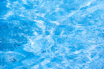 Close-up of bright blue swimming pool water surface with sunlight reflections and ripples, refreshing summer vacation and tropical luxury background.concept relex