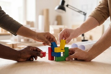 Close up of diverse hands assembling colorful wooden blocks together in a bright architectural studio