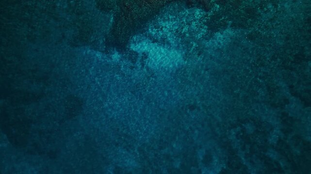 Top-down aerial drone video of deep blue ocean water over submerged reef with natural textures and subtle movement, abstract tropical seascape ideal for cinematic backgrounds and nature visuals
