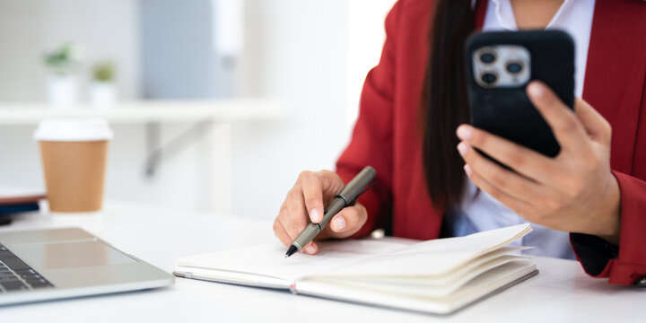 Confident business woman, writer  looking at mobile phone screen , taking notes, working project in modern office.  financier working at workplace. Successful business - Powered by Adobe
