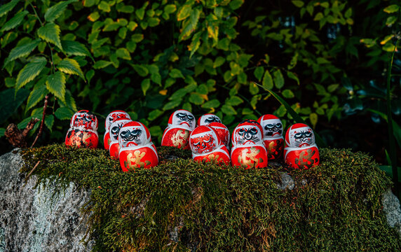 Grupo de darumas sobre una piedra con musgos en Jap&oacute;n