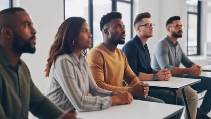 Diverse Adults Attending a Workshop in a Clean Space. Educational / eLearning & Up-skilling. Diverse group of adults seated at tables in a modern workshop listening intently to an unseen instructor.
