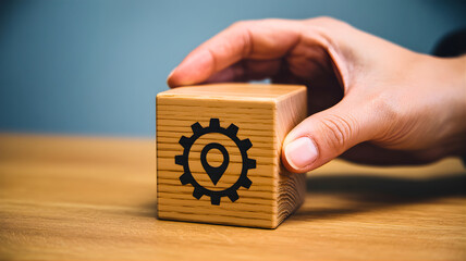 Hand interacting with a wooden block featuring a location pin and gear icon, symbolizing strategic planning, service optimization, and operational control for businesses