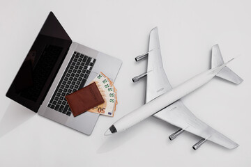Laptop, euro banknotes, brown passport, and airplane model — concept of international travel