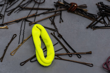 Assorted hairpins, bobby pins, and colorful hair ties scattered on a gray textured surface
