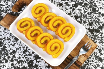 flat lay of Pineapple roll cake slices arranged on white plate, showing spiral texture and golden color, suitable for dessert and snack concepts.