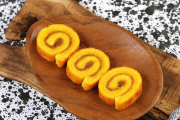 Pineapple roll cake served on rustic wooden plate with natural background.