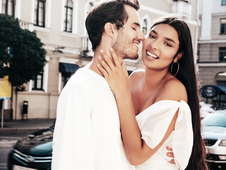 Fototapeta premium Smiling beautiful woman and her handsome boyfriend. Happy cheerful family. Sexy couple posing in the street at sunrise. During romantic date at sunny summer day outdoors. Looking at each other