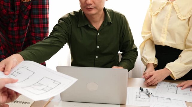 Smart architect and safety engineer discussion about building plan on table with architectural document, measurement tools and wooden block scatter around at modern office. Closeup. Delineation.