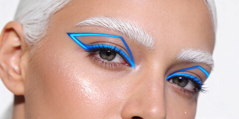 Close-up of model face with white eyebrows and neon blue geometric eyeliner makeup