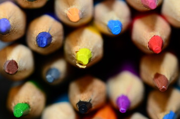 A beautiful array of coloring pencils, laying horizontally with the pencils tips pointing out to...