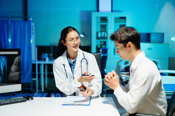 Asian female doctor consulting patient, taking medical history and explaining treatment in modern clinic