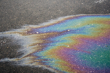 Oil slick creating abstract iridescent colors on asphalt