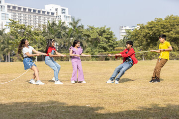 Group of playful indian kids enjoy pulling a rope during a fun outdoor tug of war game, showcasing...