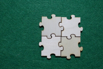 Obraz premium Four wooden puzzle pieces connected on green surface