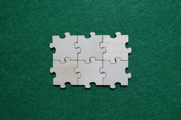 Six unfinished wooden puzzle pieces laid on green surface