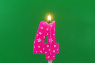 Burning pink with white stars birthday cake candle on green background. Number 4