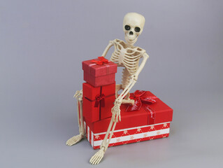 Human skeleton with red gift boxes on grey background.	