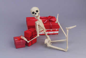 Human skeleton with red gift boxes on grey background.