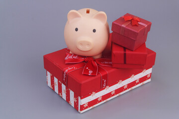 Piggy bank with red gift boxes on grey background. Good price for gifts concept.