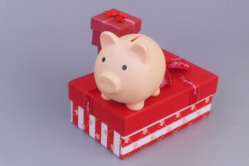 Piggy bank with red gift boxes on grey background. Good price for gifts concept.