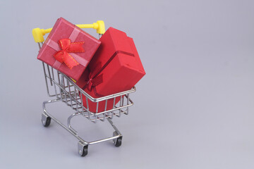 Gift boxes in shopping cart on grey background. Copy space for text. Buy gifts concept.