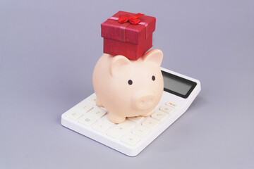 Gift box and piggy bank on calculator. Best gift price concept.
