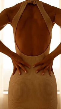 Rear View of Elegant Woman in Tight Dress Posing by Window with Hourglass Figure