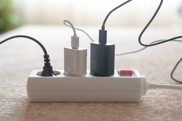Power strip with various chargers and plugs inserted, illustrating electricity consumption, energy management, and the importance of unplugging devices to save power and reduce utility bills