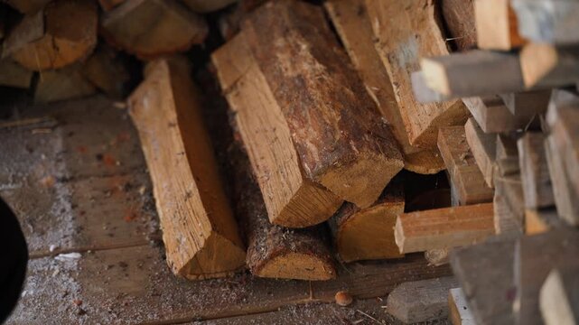 Man in gloves picks up oak firewood stacked in a woodpile, close-up