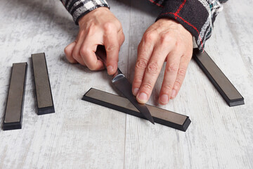 Sharpening kitchen knife on white table.