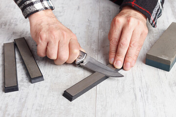 Sharpening hunting knife on white table