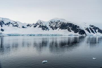 Horizontally composed shot of the rugged mountains of the Antarctic Peninsula and their reflection in the water. Danco Island, Antarctica