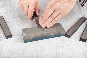 Professional sharpening small fishing knife on white table.